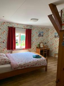 a bedroom with a bed and a window with red curtains at B&B De Kaagse Koe in Huigsloot