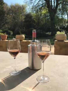 two wine glasses sitting on a table with a bottle of wine at Residence le Petit Paradis in Labastide-Rouairoux