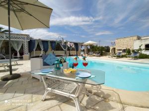 a table with wine glasses next to a swimming pool at B&B Tenuta Martinelli in Monopoli