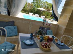 a table with a plate of food on it in a room with a pool at B&B Tenuta Martinelli in Monopoli