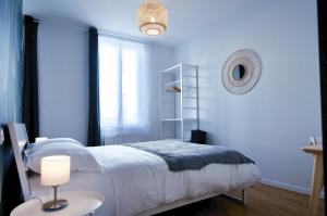 Un dormitorio azul con una cama blanca y una ventana en NuitéeJour Niort Centre en Niort