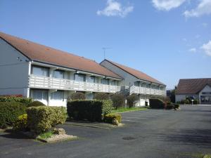 un grand bâtiment blanc avec un parking dans l'établissement Kyriad Châteauroux - Saint-Maur, à Saint-Maur