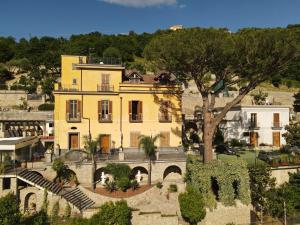 un grand bâtiment jaune avec un arbre devant lui dans l'établissement Villa Di Natale, à Pagani