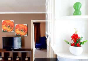 een woonkamer met een televisie en een vaas met bloemen bij Kalliopi's apartment in Athene