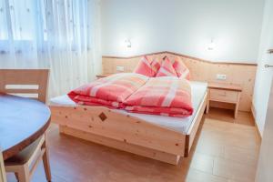 Un dormitorio con una cama de madera con almohadas rojas y blancas. en Hofschenke Pfeiftal - Bergwiese, en San Martino