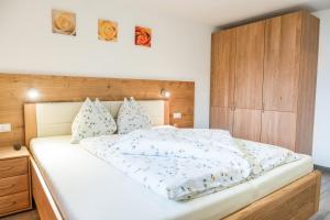 een slaapkamer met een groot wit bed met een houten hoofdeinde bij Hofschenke Pfeiftal - Almenrausch in San Martino