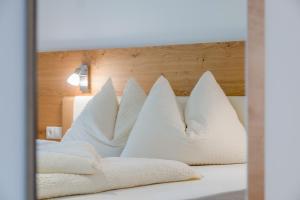een bed met witte kussens en een houten hoofdeinde bij Hofschenke Pfeiftal - Hofblick in San Martino