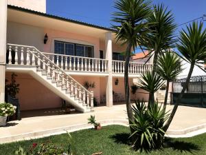a house with a staircase and palm trees in the yard at Caroça House in Nazaré