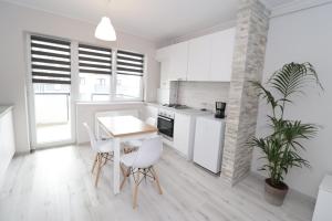 cocina con armarios blancos, mesa y sillas en Apartament 2 camere Anto en Sibiu