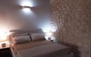 - une chambre avec un mur en pierre et un lit avec deux lampes dans l'établissement AL PEZ exclusive rooms, à Olbia