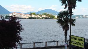een uitzicht op een waterlichaam met een hotel met een bord bij Hotel Villa Ruscello in Baveno