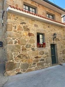 a stone building with a green door and two windows at Casita Piñeiro estilo rural in Boiro