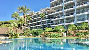 a hotel with a swimming pool in front of a building at MI CAPRICHO 3-5 BEACHFRONT- Apartment with sea views in Costa del Sol in Mijas Costa