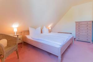 a bedroom with a white bed and a dresser at Ferienhaussiedlung Strandperlen Buchenhof 4d (Typ IV) in Wustrow