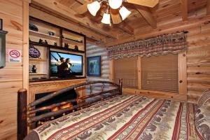 ein Schlafzimmer mit einem Bett und einem TV in einer Blockhütte in der Unterkunft Kiss Me Goodnight in Sevierville