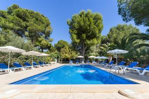 a swimming pool with chairs and umbrellas at Hotel Cala Murada in Cala Murada