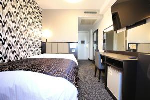 佐賀市にあるアパホテル 佐賀駅南口のベッドとデスクが備わるホテルルームです。