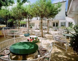 eine Terrasse mit Tischen, Stühlen und Bäumen in der Unterkunft Hotel Walter in Gatteo a Mare
