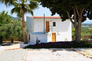 a white house with a tree and purple flowers at Casita of Casa Olivar in Tocon