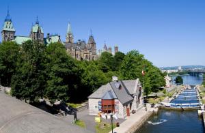 a building next to a body of water with a castle at Les Suites Hotel in Ottawa