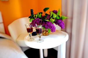 a table with two glasses of wine and a bouquet of purple flowers at Apartament Sianożęty in Sianozety +8 photos