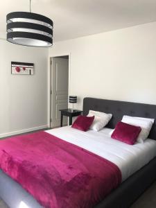 Un dormitorio con una cama grande con una manta roja. en Le Nid du Franc, en Avranches