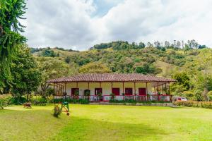een huis in het midden van een veld met een grasveld bij La Cabaña Ecohotel - Valle del Cocora in Salento