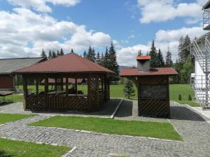 a wooden gazebo with a grill in a yard at Vila Sport Borsec in Borsec