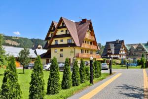 a large house with a pointed roof on a street at Kwatery Prywatne Beata Marek in Białka Tatrzańska