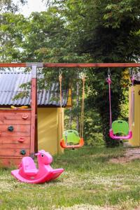 a play structure with two swings and a pink duck toy at Бунгала Камена - Bungalows Kamena in Kamena