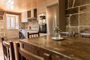 een keuken met een houten tafel en een vaas met bloemen erop bij Casa dos Muiños in Pontevedra