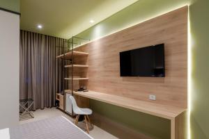 a room with a desk with a television on a wall at Avenida Hotel in Sorriso