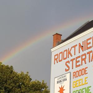 een regenboog boven een gebouw met een rotsblok bij B&B The Project in Heerlen
