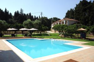 a large blue swimming pool in a yard with umbrellas at Eleas gi (Olive Grove Estate) in Tsilivi