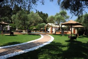 una pasarela en un parque con mesas y sombrillas en Eleas gi (Olive Grove Estate), en Tsilivi