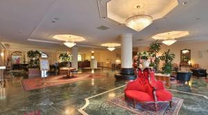un gran vestíbulo con una silla roja en el medio en Best Western Hotel Globus City, en Forlì