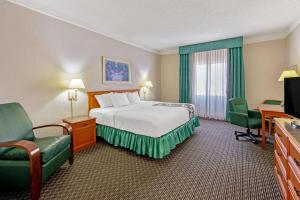 a hotel room with a bed and chairs and a television at La Quinta Inn by Wyndham Las Cruces Mesilla Valley in Las Cruces
