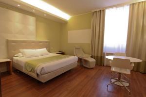 una camera d'albergo con letto, scrivania e finestra di Best Western Mirage Hotel Fiera a Paderno Dugnano