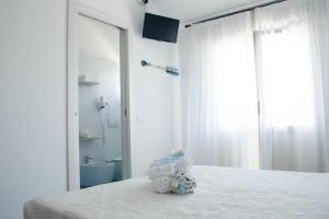 a white bedroom with a bed with a bathroom at Albergo Medusa in Punta Marina