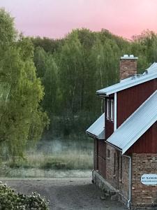 un edificio rojo con chimenea junto a un bosque en Sjöborg Säng & Bassäng en Munka-Ljungby