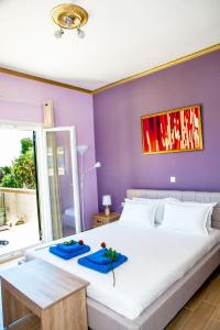 a bedroom with a large white bed with purple walls at FilipposResort in Agios Gordios