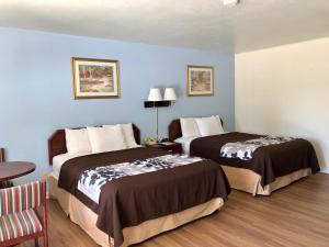 2 camas en una habitación de hotel con paredes azules en The Budget Inn Express, en Sheridan