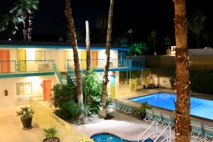a resort with a pool and palm trees at night at Adara Palm Springs in Palm Springs