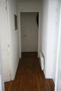 een lege hal met een houten vloer en een witte deur bij Appartement Opéra Paris in Parijs