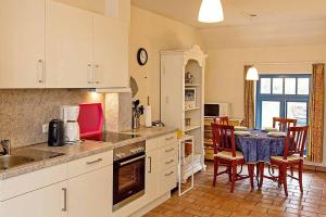 une cuisine avec des armoires blanches et une table et des chaises dans l'établissement Ferienhaussiedlung Strandperlen Weidenhof 8b (Typ V), à Wustrow 11 autres photos