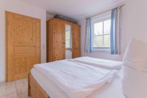 ein Schlafzimmer mit einem weißen Bett und einem Fenster in der Unterkunft Haus WINDFLÜCHTER Whg. LF 6.1 in Wustrow