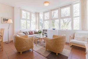 un soggiorno con divano, sedie e finestre di Haus LONGARD a Ahrenshoop