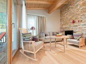 ein Wohnzimmer mit einem Sofa, Stühlen und einem Tisch in der Unterkunft Ferienwohnungen am Travel Charme Bergresort Werfenweng in Werfenweng