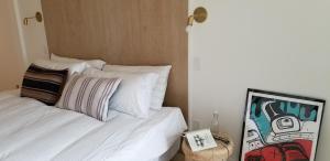 a bedroom with a bed with white sheets and a painting at 378 Marine Drive in Ucluelet