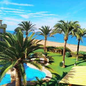 Blick auf ein Resort mit Palmen und den Strand in der Unterkunft Estupendo apartamento en primera línea de playa y con vistas al mar in Denia
